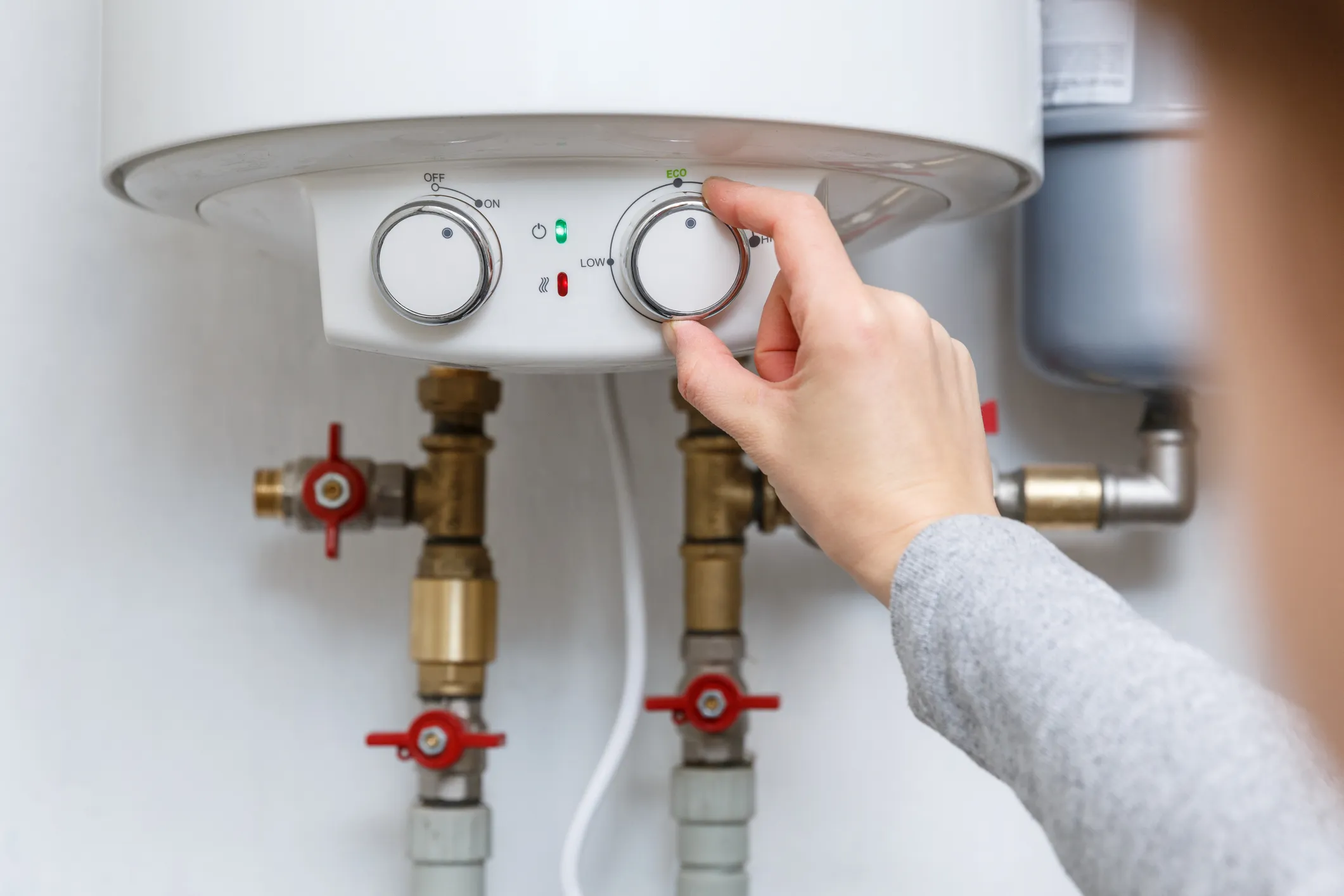 A person adjusting knobs on an electric water heater in Des Moines, IA.